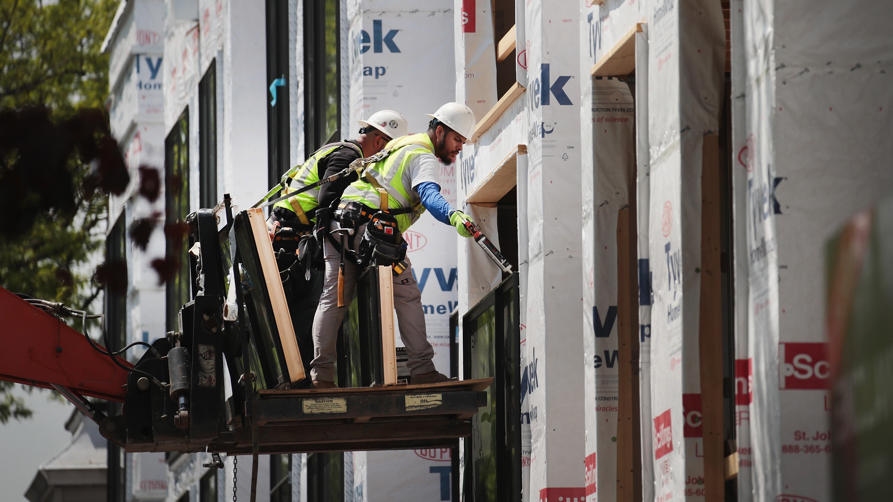 Workers install windows in a townhome complex under construction