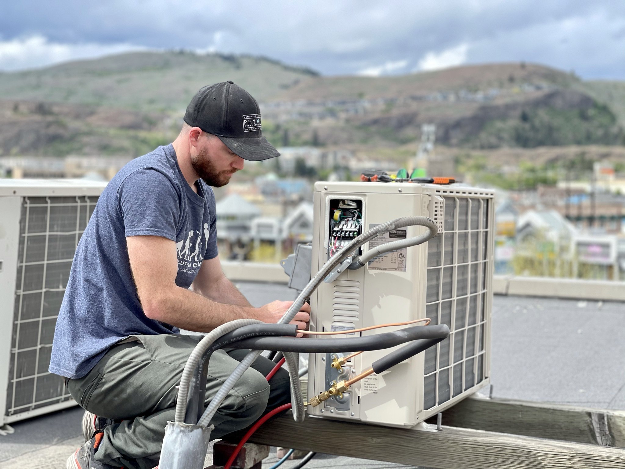 A man installs a ductless heat pump on a roof  © 2021 Vernon Air Conditioning/Flickr CC BY 4.0 