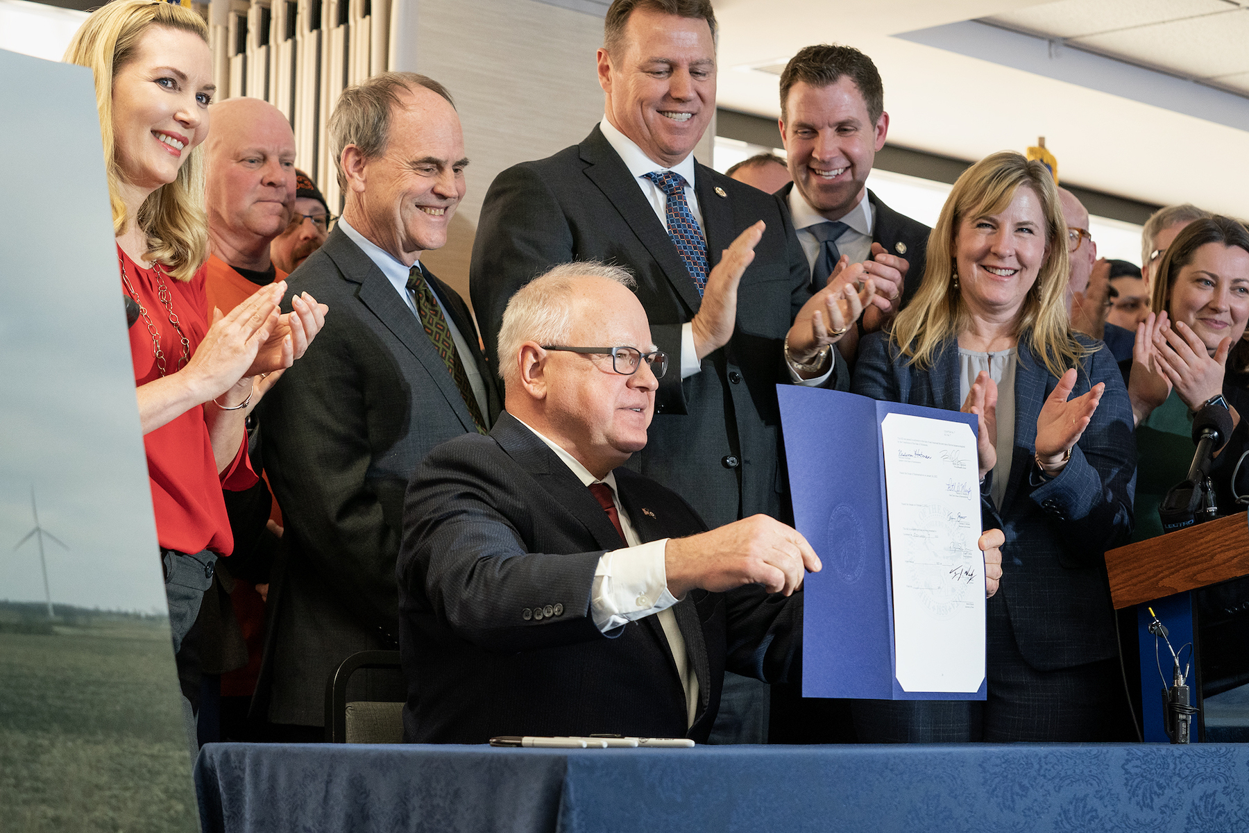 Governor Tim Walz holding up clean energy bill