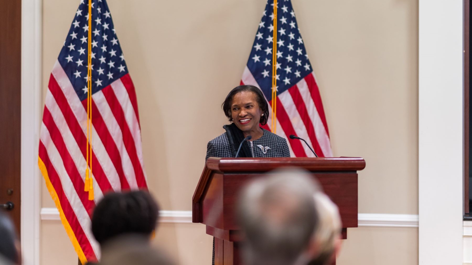 CEQ chair Brenda Mallory speaking at a podium in front of two U.S. flags.