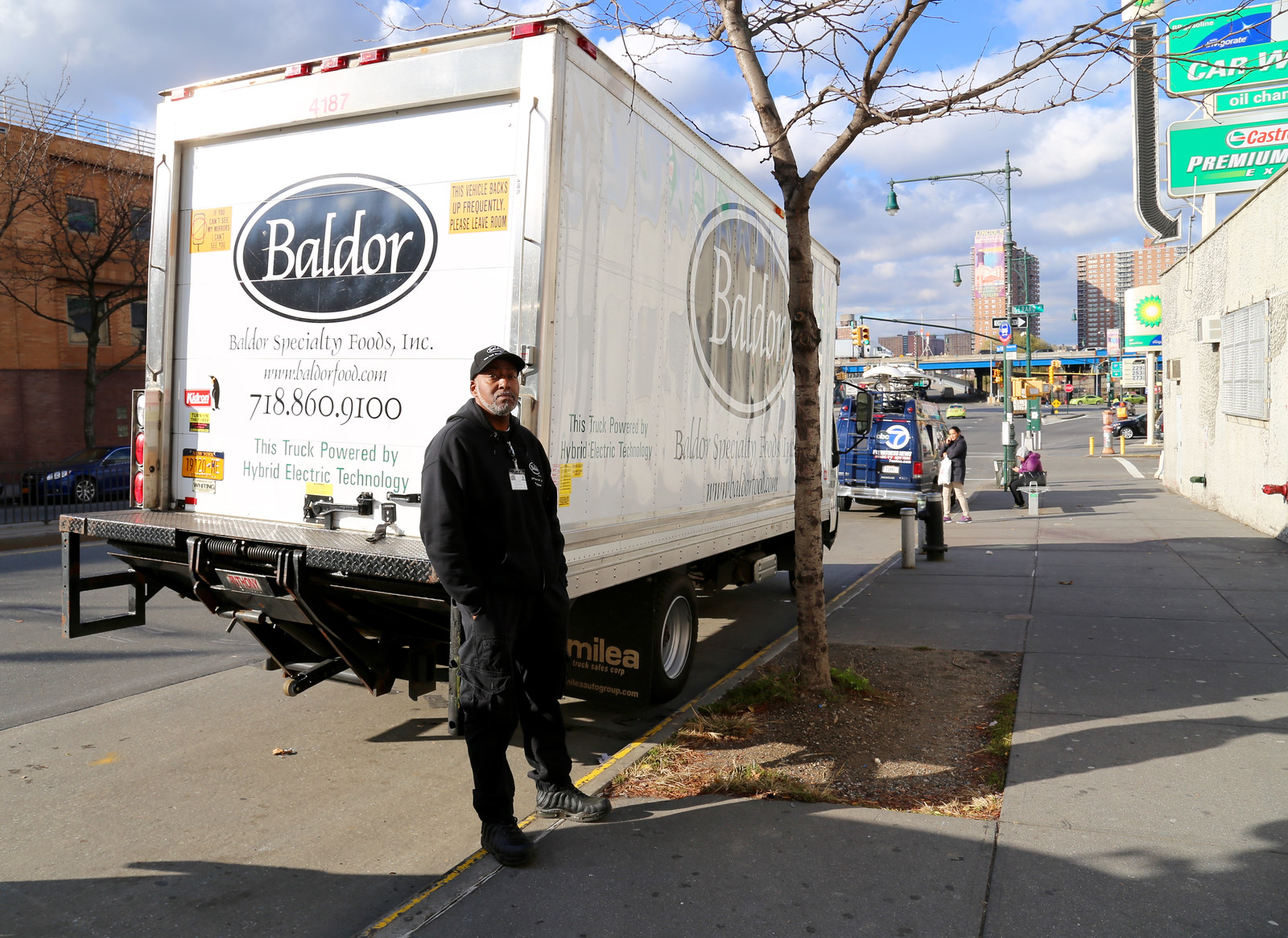 Man standing in front of the back of a large white truck in the city.