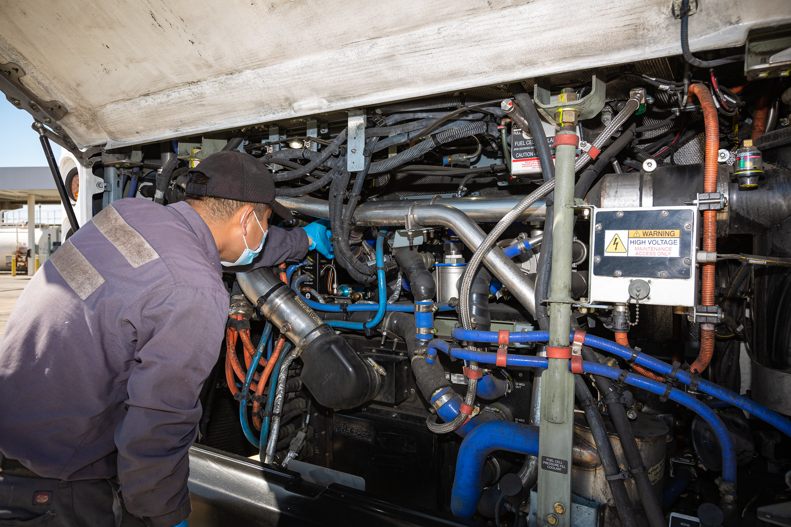 A worker inspecting the battery of an electric bus up close.