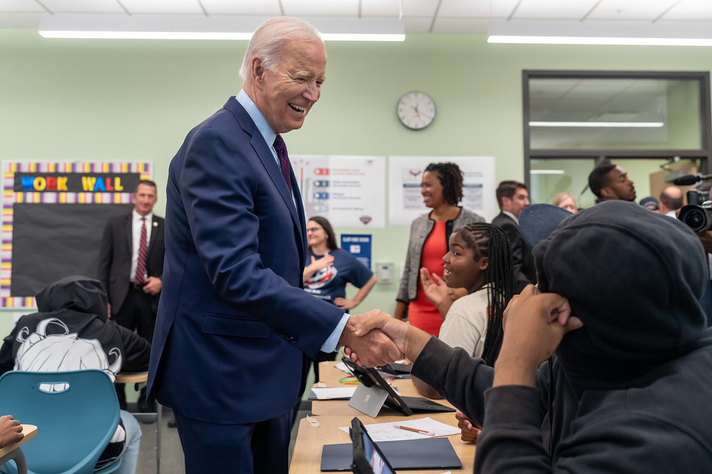 President Biden shaking a student's hand in a classroom.
