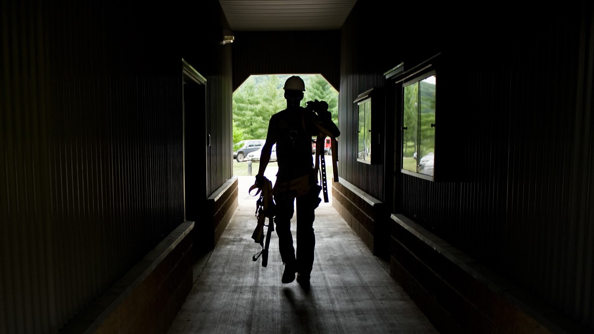 A solar panel technician carrying equipment down a hall.