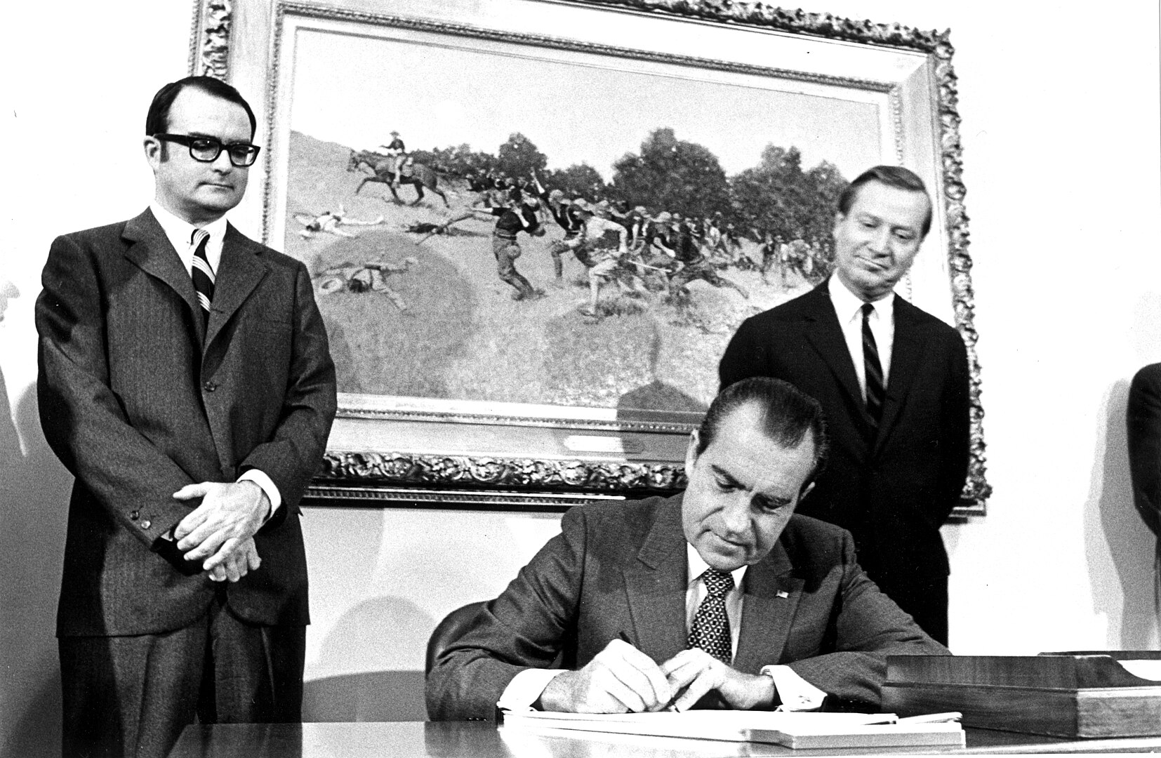 Black and white photo of President Nixon seated, looking down, and signing the Clean Air Act amendments.