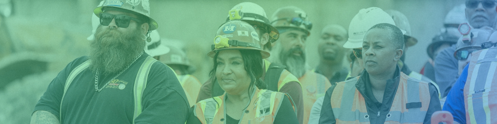 Three workers in orange hard hats and vests standing next to one another.