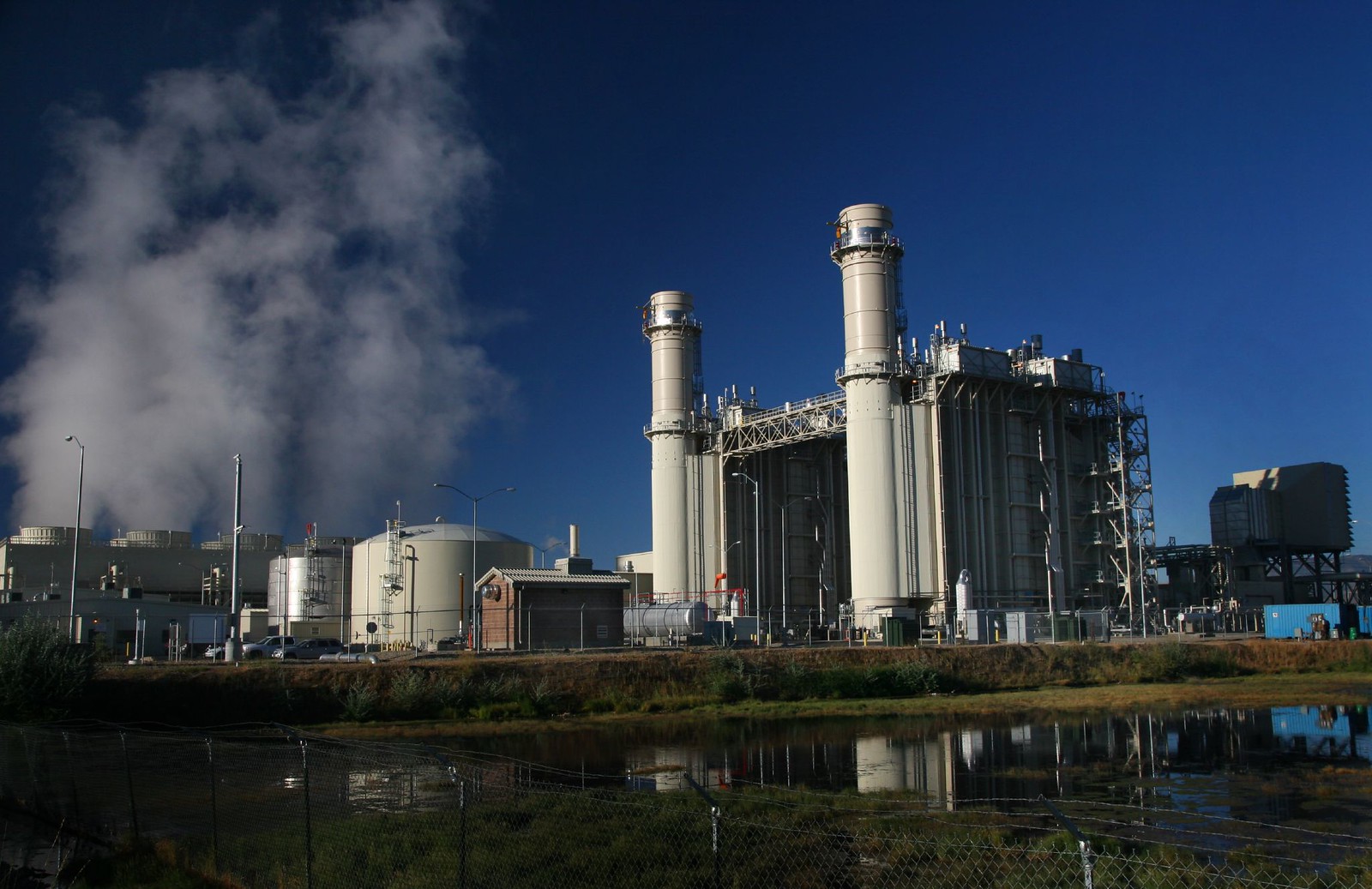 A wide angle shot of a white gas power plant. Exhaust is seen coming out of the side structures.