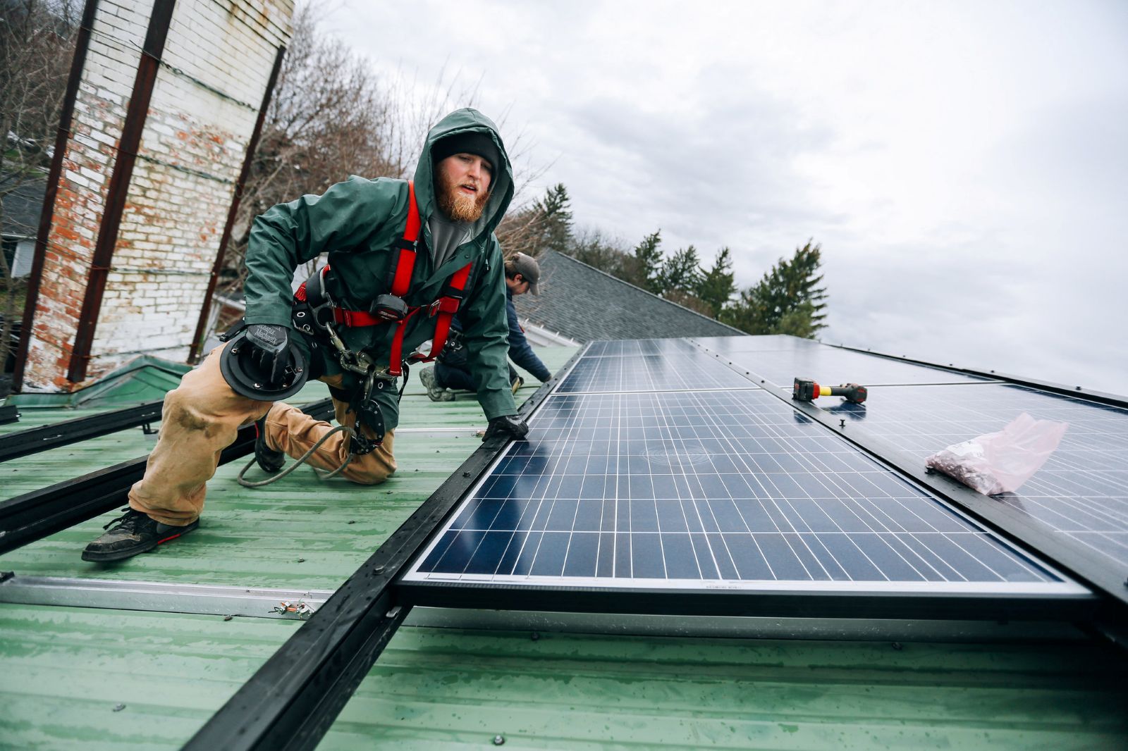 Man installing a solar panel on a roof in New York.