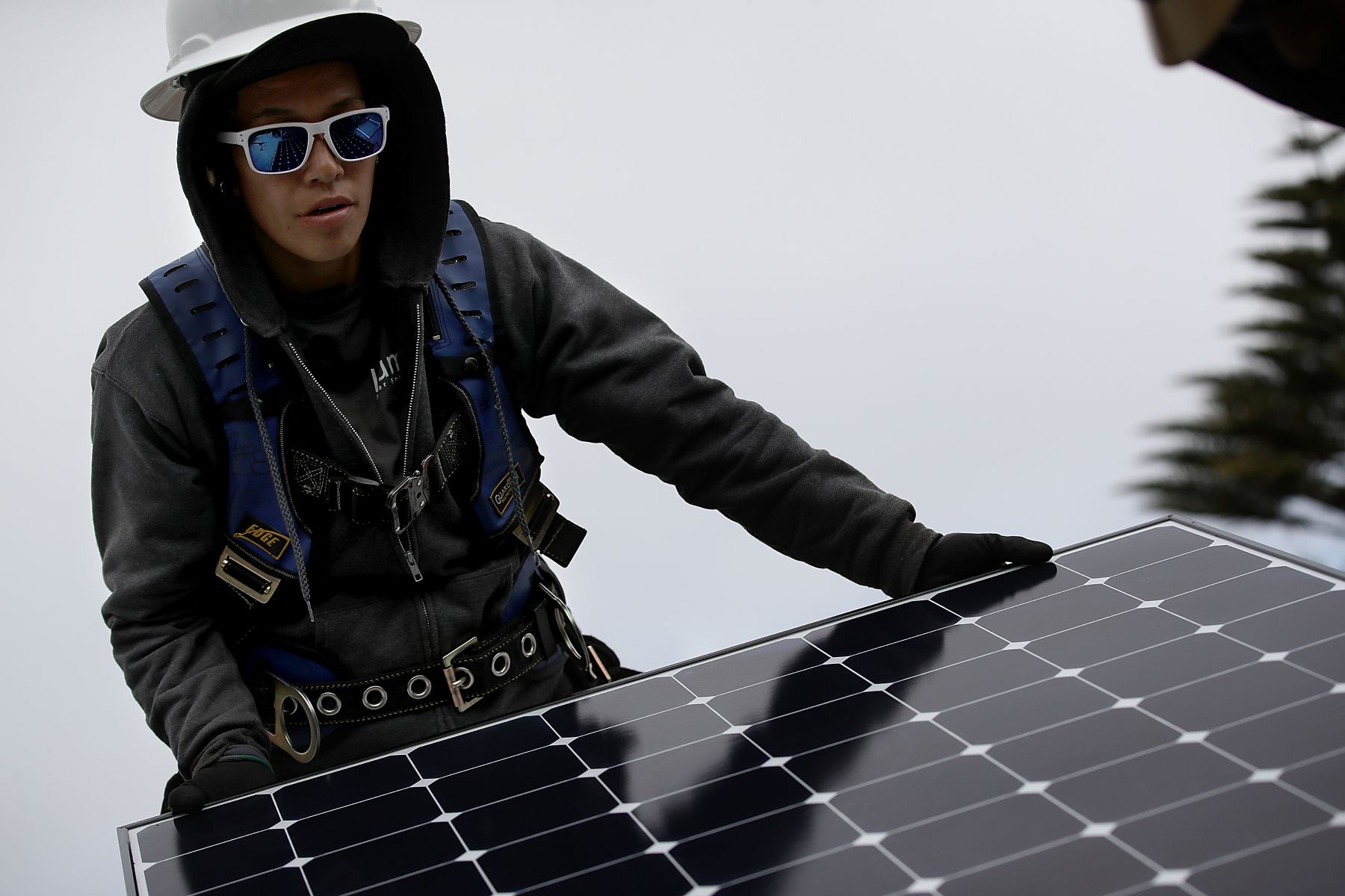 Up close shot of a worker moving a solar panel during an installation on a roof