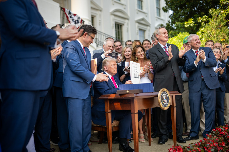 Trump signs the One Big Beautiful Bill Act at the White House, surrounded by Republicans. 