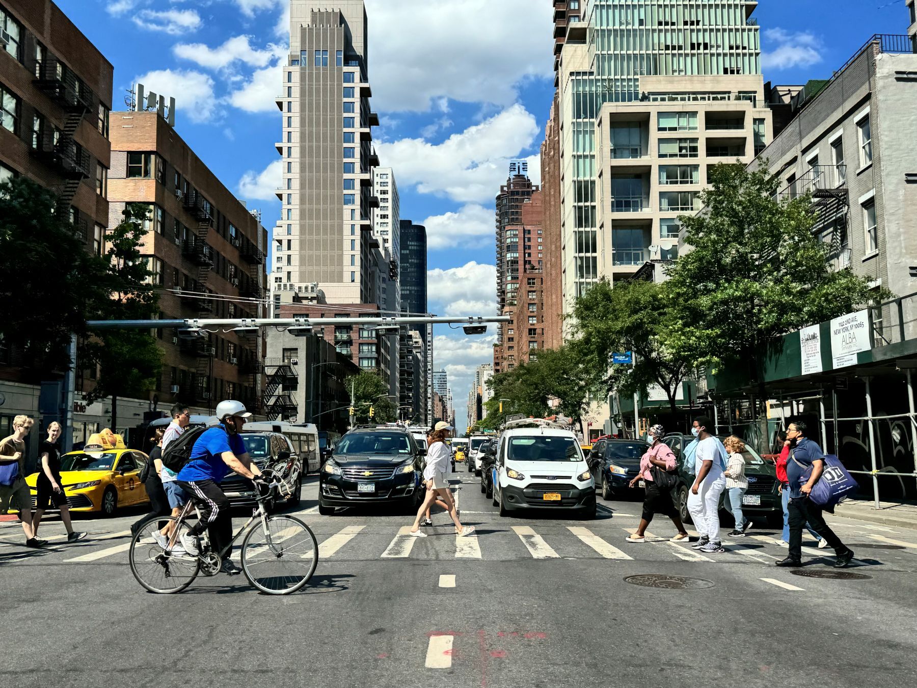 People walking under automatic congestion pricing toll machines in Manhattan.