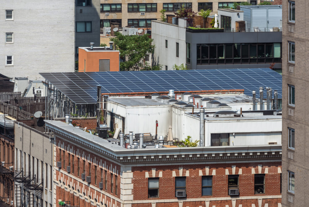An aerial view of East Village in New York featuring solar panels on the roof of an apartment building on Third Avenue.