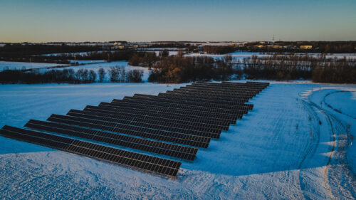 Aerial view of rows of solar panels in a rural area of Wisconsin, with snow covering the ground